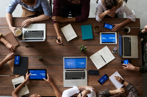 people sitting at table with laptops and devices